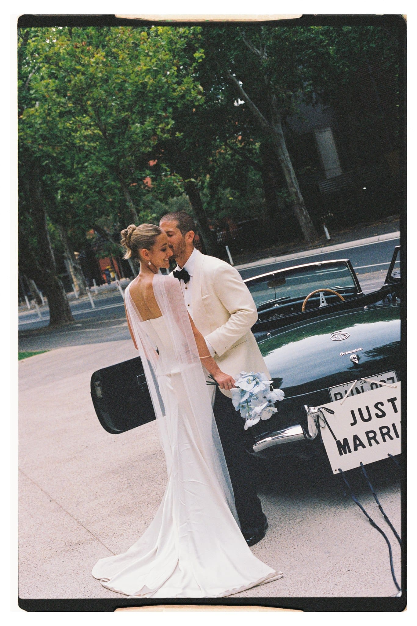 Film photo of bride and groom and their wedding car in Adelaide